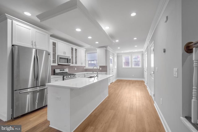 kitchen with backsplash, sink, light wood-type flooring, appliances with stainless steel finishes, and white cabinetry