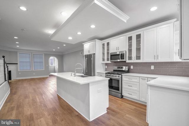 kitchen featuring white cabinetry, sink, stainless steel appliances, backsplash, and a kitchen island with sink