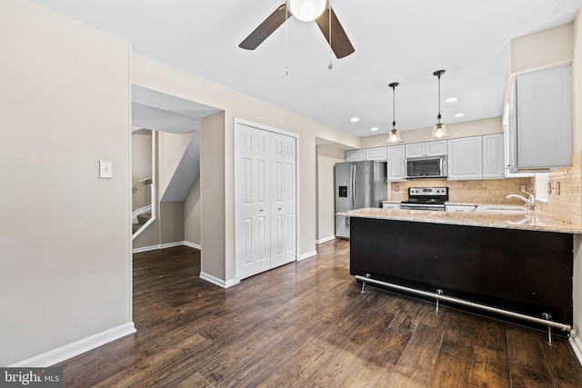 kitchen featuring pendant lighting, sink, ceiling fan, appliances with stainless steel finishes, and light stone counters