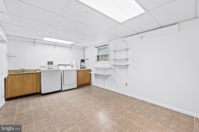 clothes washing area with washer and clothes dryer, cabinets, and sink