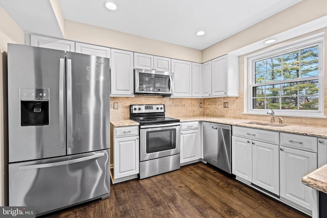 kitchen featuring light stone countertops, sink, stainless steel appliances, dark hardwood / wood-style floors, and white cabinets