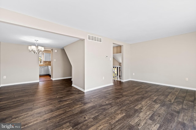 unfurnished living room featuring dark hardwood / wood-style floors, lofted ceiling, and an inviting chandelier