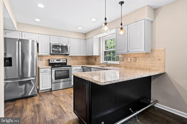 kitchen with white cabinets, dark hardwood / wood-style flooring, kitchen peninsula, and stainless steel appliances