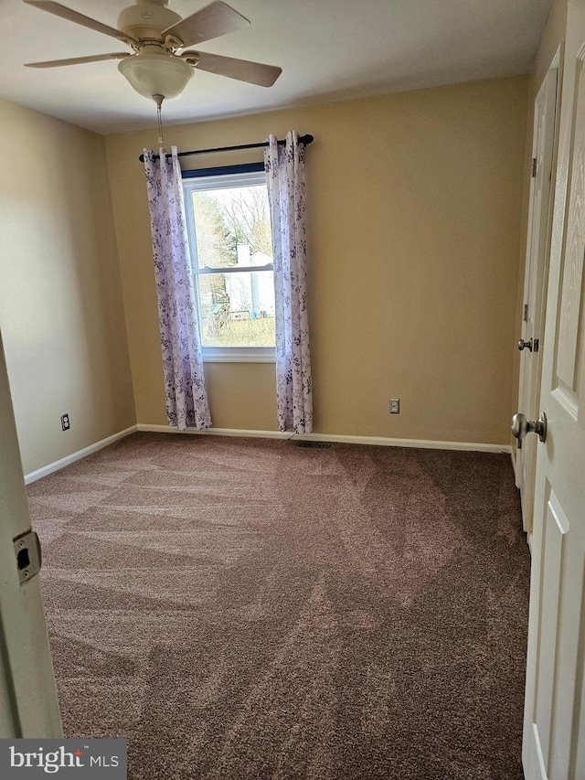 empty room with carpet flooring, a ceiling fan, and baseboards