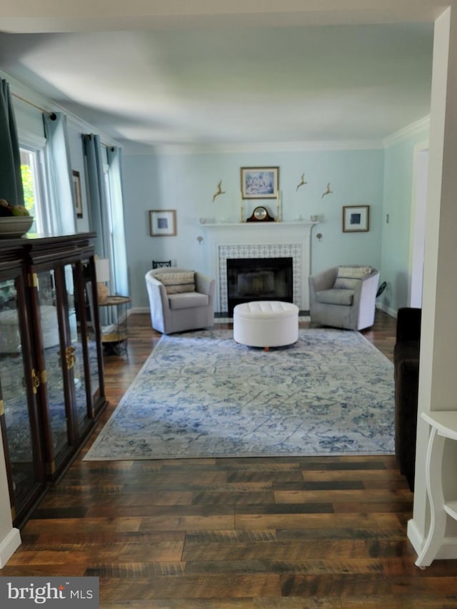 living area featuring baseboards, dark wood-style floors, a fireplace, and ornamental molding