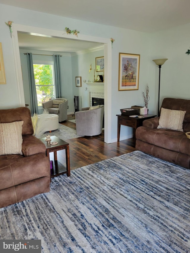 living area with ornamental molding, a fireplace, baseboards, and wood finished floors