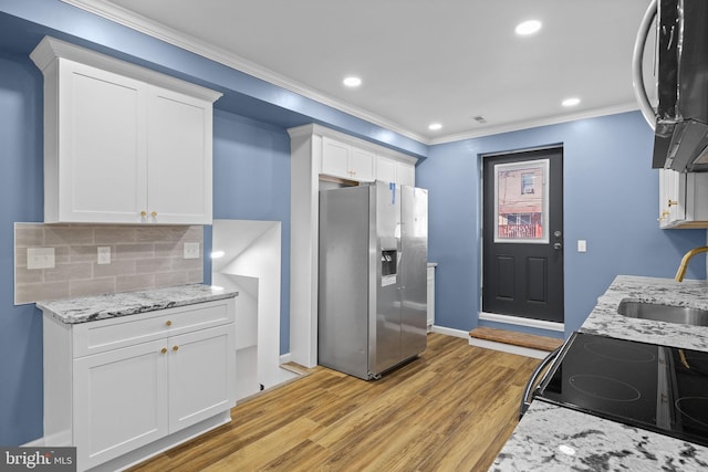 kitchen with white cabinetry, tasteful backsplash, stainless steel fridge, and sink