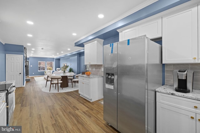 kitchen with decorative backsplash, light stone countertops, stainless steel appliances, light hardwood / wood-style flooring, and white cabinetry