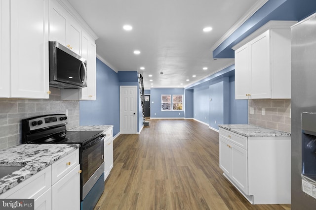 kitchen with backsplash, stainless steel appliances, white cabinetry, and ornamental molding