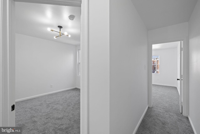 hallway featuring carpet flooring and a notable chandelier