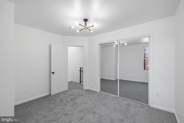 unfurnished bedroom featuring a chandelier, carpet floors, and a closet