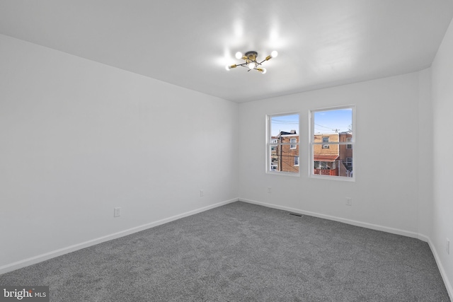 carpeted empty room with a chandelier