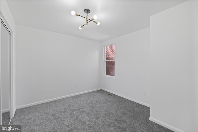 carpeted empty room featuring an inviting chandelier