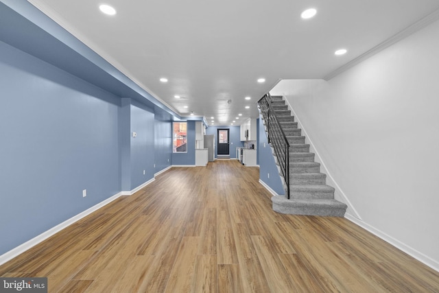 unfurnished living room with light hardwood / wood-style flooring and crown molding