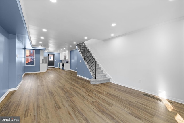 unfurnished living room featuring crown molding and hardwood / wood-style floors