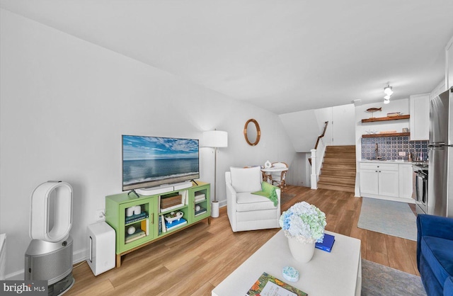 living room featuring light wood-type flooring and vaulted ceiling