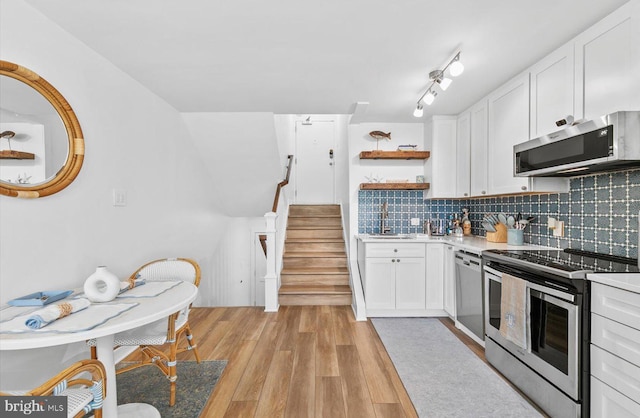 kitchen featuring light hardwood / wood-style floors, white cabinetry, stainless steel appliances, and tasteful backsplash