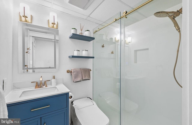 bathroom with toilet, a drop ceiling, vanity, and walk in shower