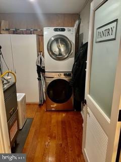 clothes washing area with stacked washing maching and dryer and dark wood-type flooring