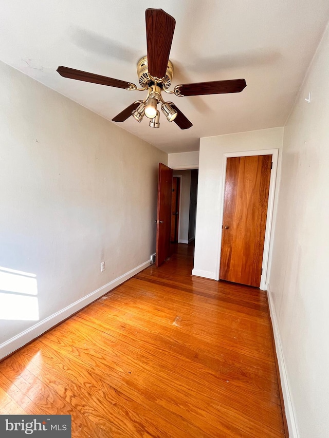 unfurnished bedroom featuring ceiling fan, a closet, and hardwood / wood-style flooring