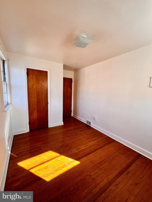 unfurnished bedroom with a closet and dark hardwood / wood-style flooring