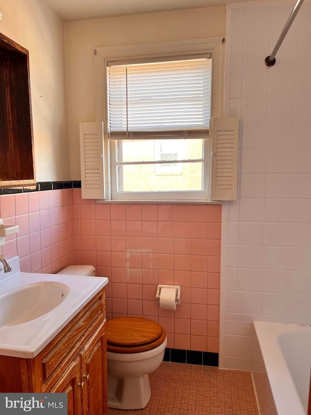 full bathroom with toilet, independent shower and bath, tile patterned flooring, tile walls, and vanity