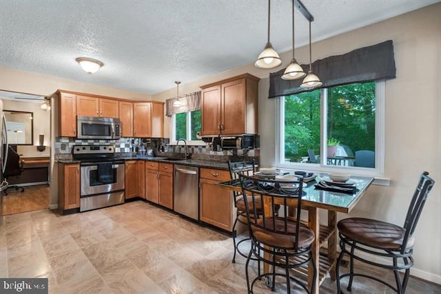 kitchen featuring decorative light fixtures, appliances with stainless steel finishes, a wealth of natural light, and sink