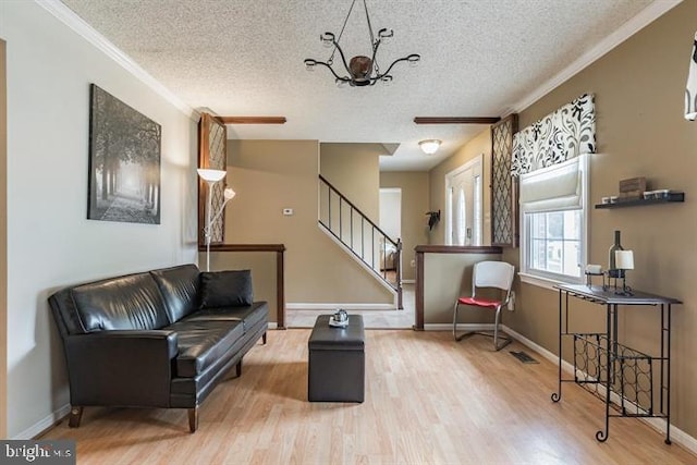 living area with a textured ceiling, ornamental molding, a chandelier, and hardwood / wood-style floors