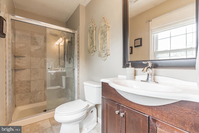 bathroom featuring a textured ceiling, a shower with door, vanity, and toilet