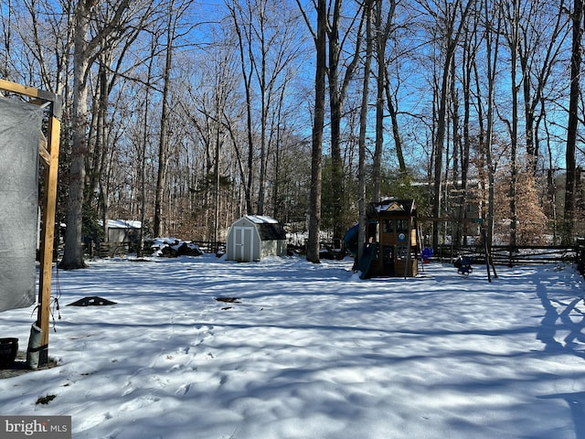 yard layered in snow with a playground and a shed