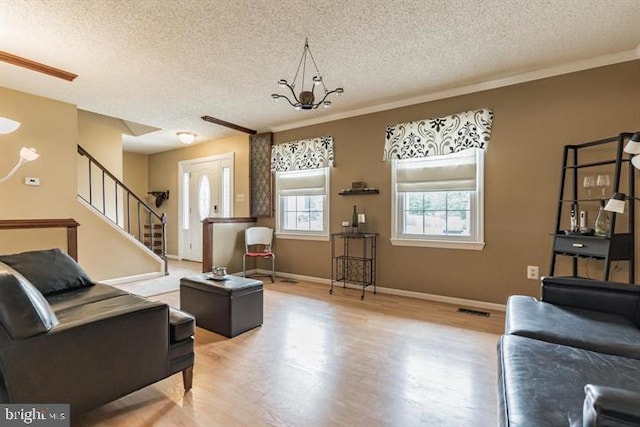 living room with a textured ceiling, an inviting chandelier, hardwood / wood-style flooring, and crown molding