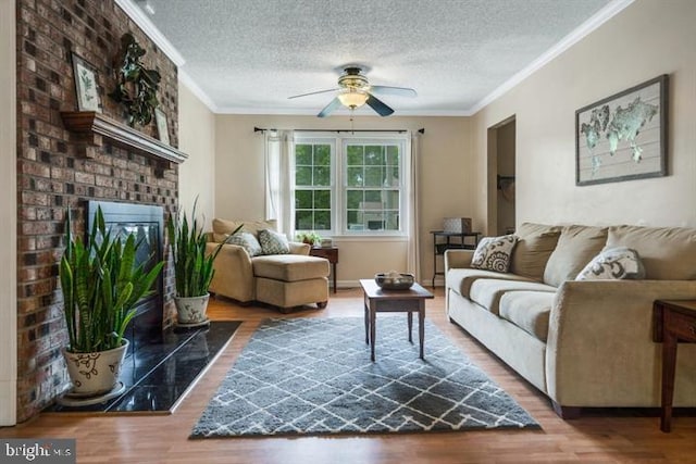 living room with a fireplace, a textured ceiling, ceiling fan, hardwood / wood-style flooring, and crown molding