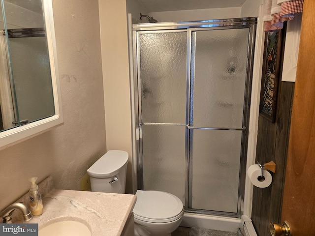 bathroom with vanity, toilet, a shower with shower door, and baseboard heating