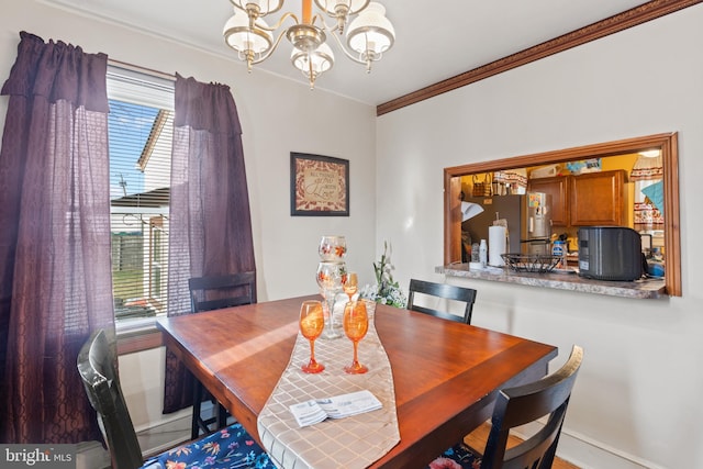 dining room featuring a wealth of natural light, ornamental molding, and an inviting chandelier