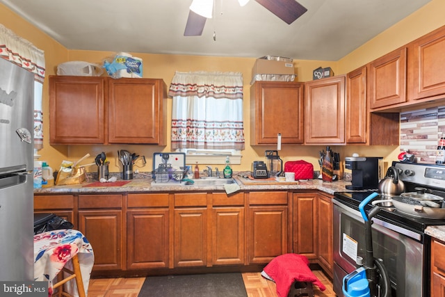 kitchen with light stone countertops, ceiling fan, sink, stainless steel appliances, and parquet flooring