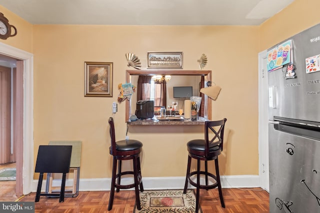 kitchen featuring kitchen peninsula, stainless steel fridge, parquet floors, and a breakfast bar area