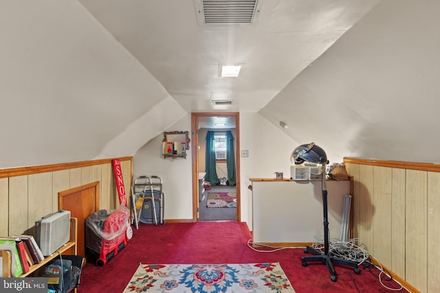 recreation room featuring wood walls, vaulted ceiling, and dark colored carpet