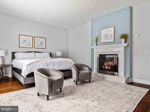 bedroom featuring hardwood / wood-style flooring and a premium fireplace