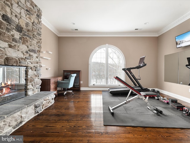 workout room featuring a fireplace, crown molding, and dark wood-type flooring