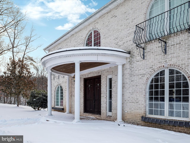 snow covered property entrance with a balcony