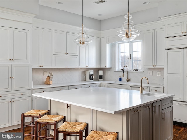 kitchen featuring a breakfast bar, sink, decorative backsplash, and an island with sink