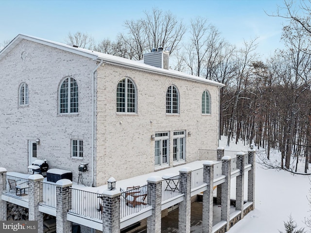 snow covered back of property with a deck