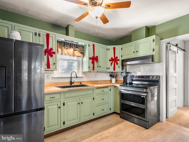 kitchen featuring appliances with stainless steel finishes, light wood-type flooring, backsplash, and sink