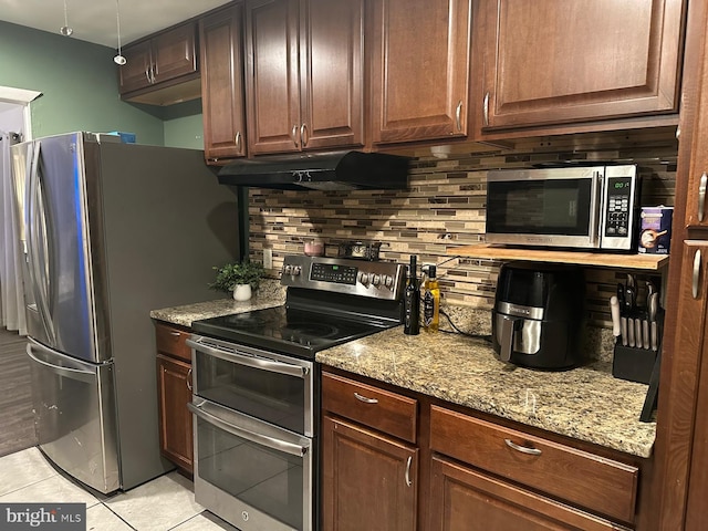 kitchen featuring tasteful backsplash, appliances with stainless steel finishes, light tile patterned floors, and light stone counters