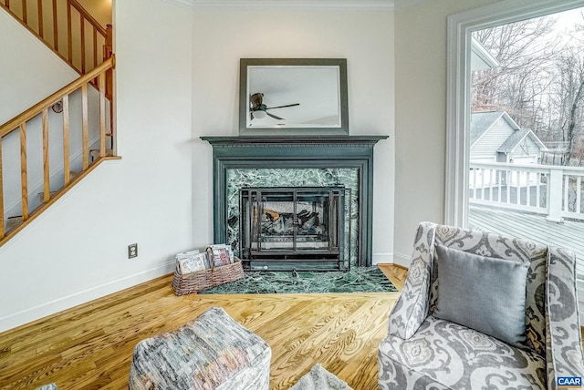 sitting room with a high end fireplace, hardwood / wood-style floors, ceiling fan, and ornamental molding