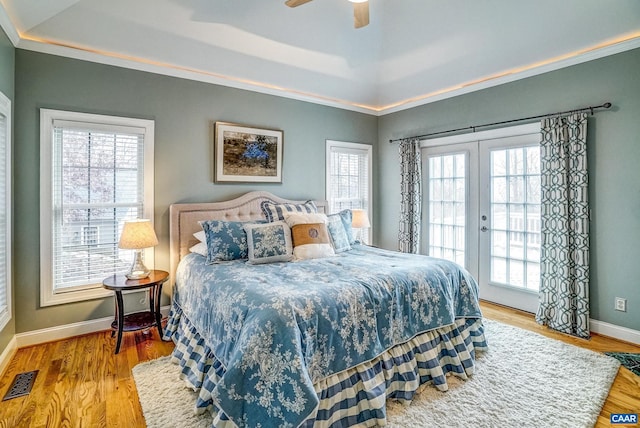 bedroom featuring french doors, hardwood / wood-style flooring, ceiling fan, access to exterior, and a tray ceiling