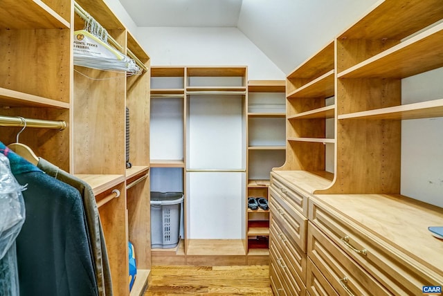 spacious closet with light hardwood / wood-style flooring and lofted ceiling