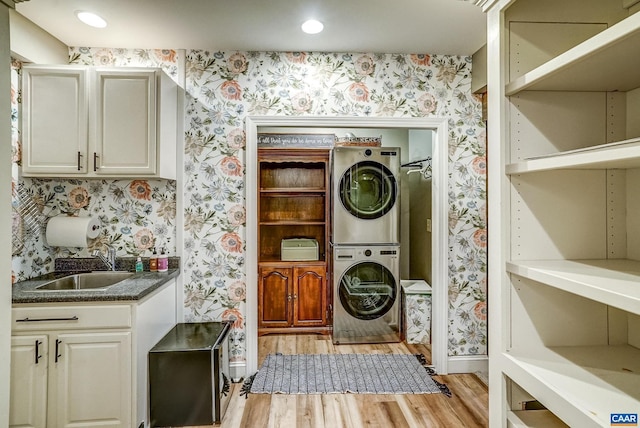 laundry area with light hardwood / wood-style flooring, sink, and stacked washer and clothes dryer