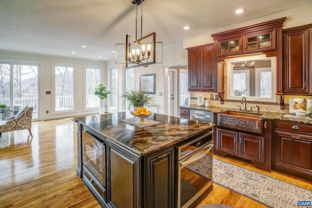 kitchen with dark stone counters, sink, a kitchen island, stainless steel appliances, and a chandelier