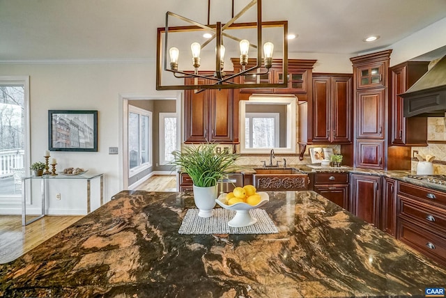 kitchen featuring sink, dark stone counters, a chandelier, decorative light fixtures, and decorative backsplash